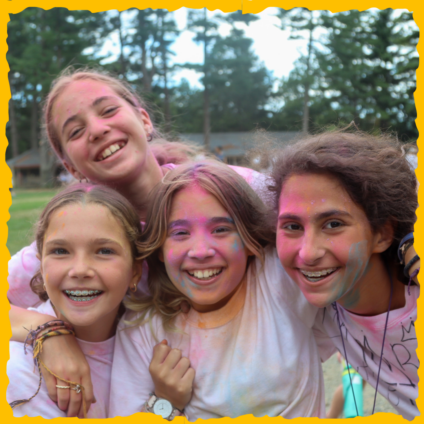 Four female campers hugging and smiling together.